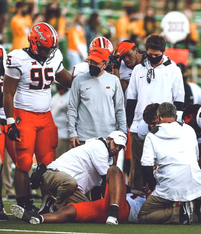 athletic trainers kneel next to an injured OSU football player