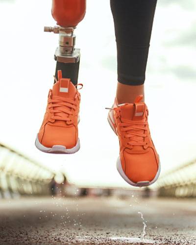 prosthetic leg mid jump wearing orange tennis shoes